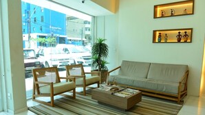 A modern living room with a sofa, two armchairs, a coffee table, and a potted plant. - Alpha Praia Hotel (Fortaleza)