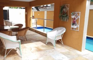 A sunlit indoor area with wicker furniture, a pool, and a view of the outside. - Alpha Praia Hotel (Fortaleza)