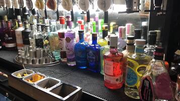 A bar with various bottles of alcohol, including gin and vodka, and a tray with orange slices.