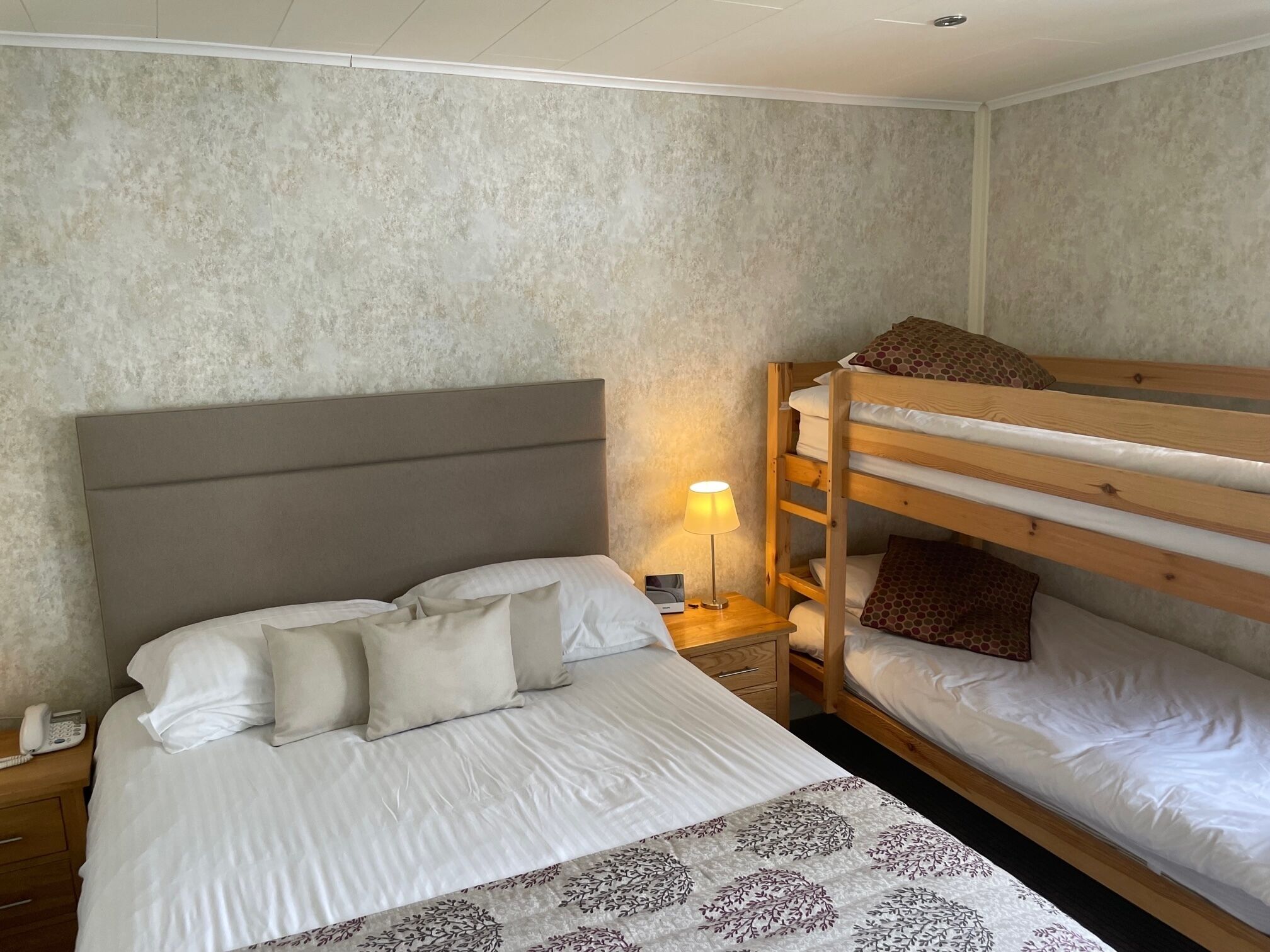 Quarto com uma cama de solteiro, mesa de cabeceira com abajur e uma cama beliche.