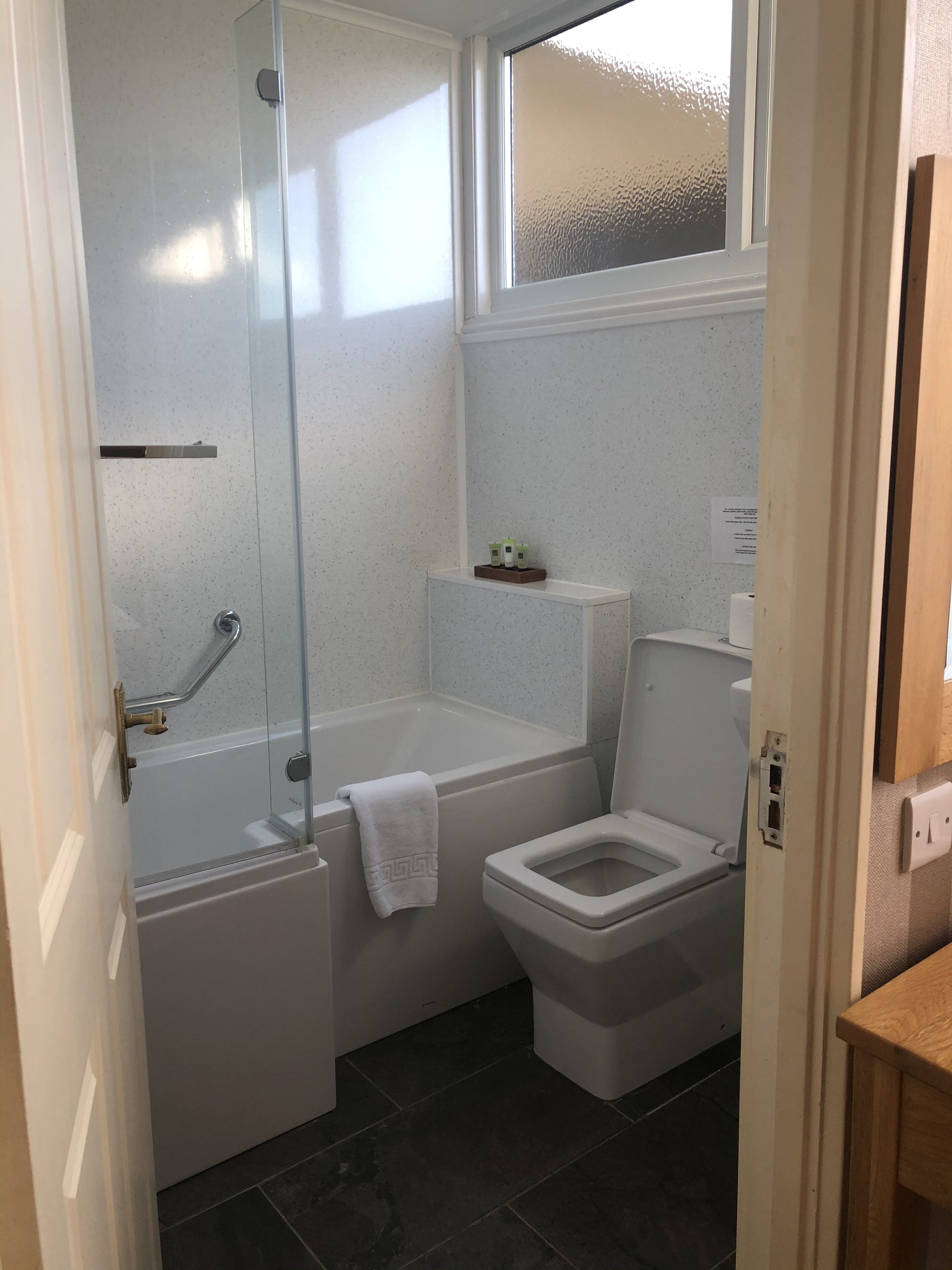 A bathroom with a glass-enclosed shower, a bathtub, and a toilet.