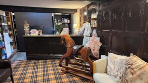 A room with a plaid carpet, a rocking horse, a sofa, and a counter with various items. - The Dog and Partridge Country Inn (Ashbourne)