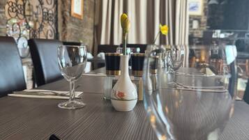 A restaurant table with a 'RESERVED' sign, wine glasses, and a vase with a yellow flower.