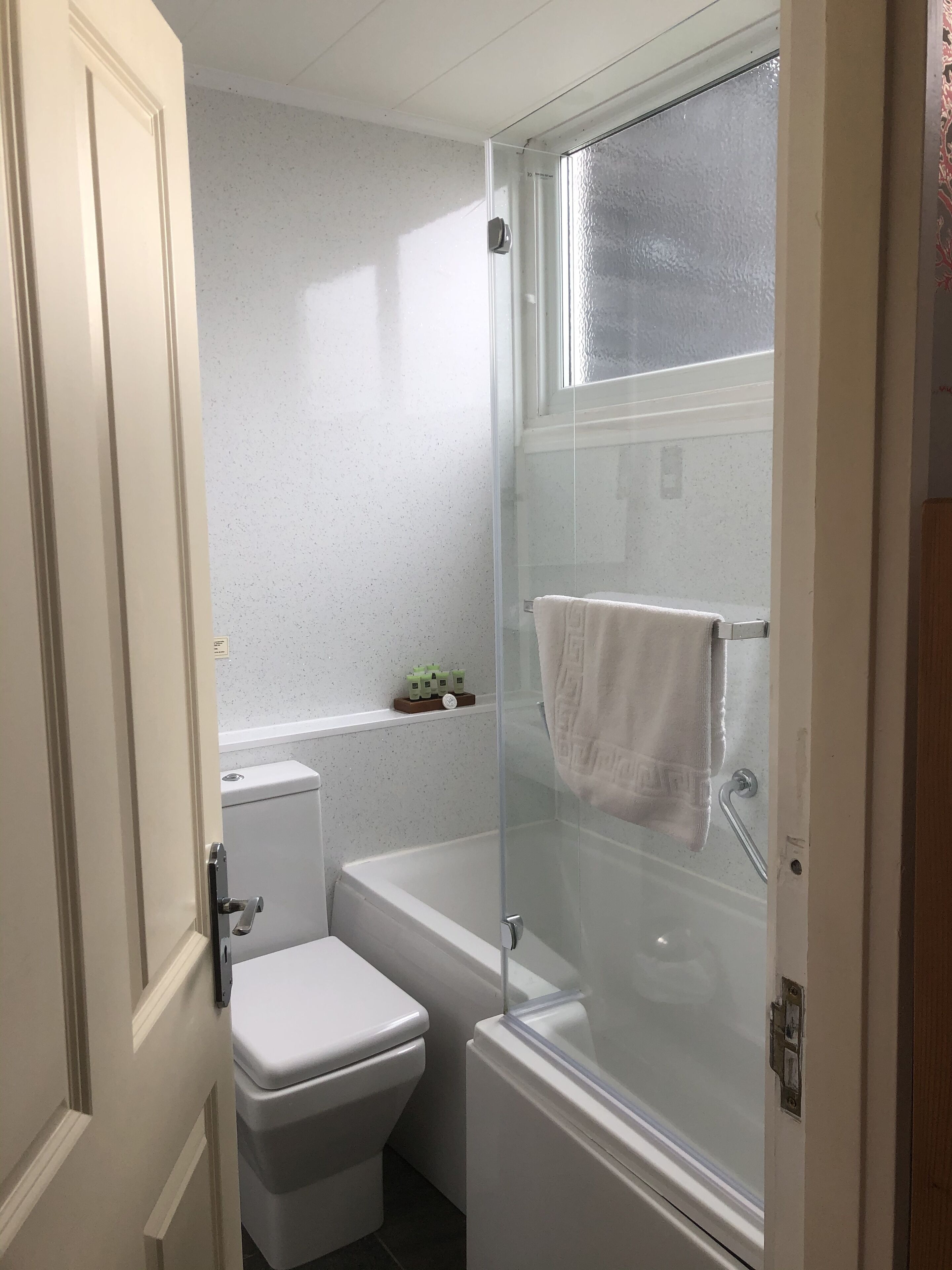Une salle de bain équipée de toilettes, d’une baignoire et d’une douche à parois de verre.