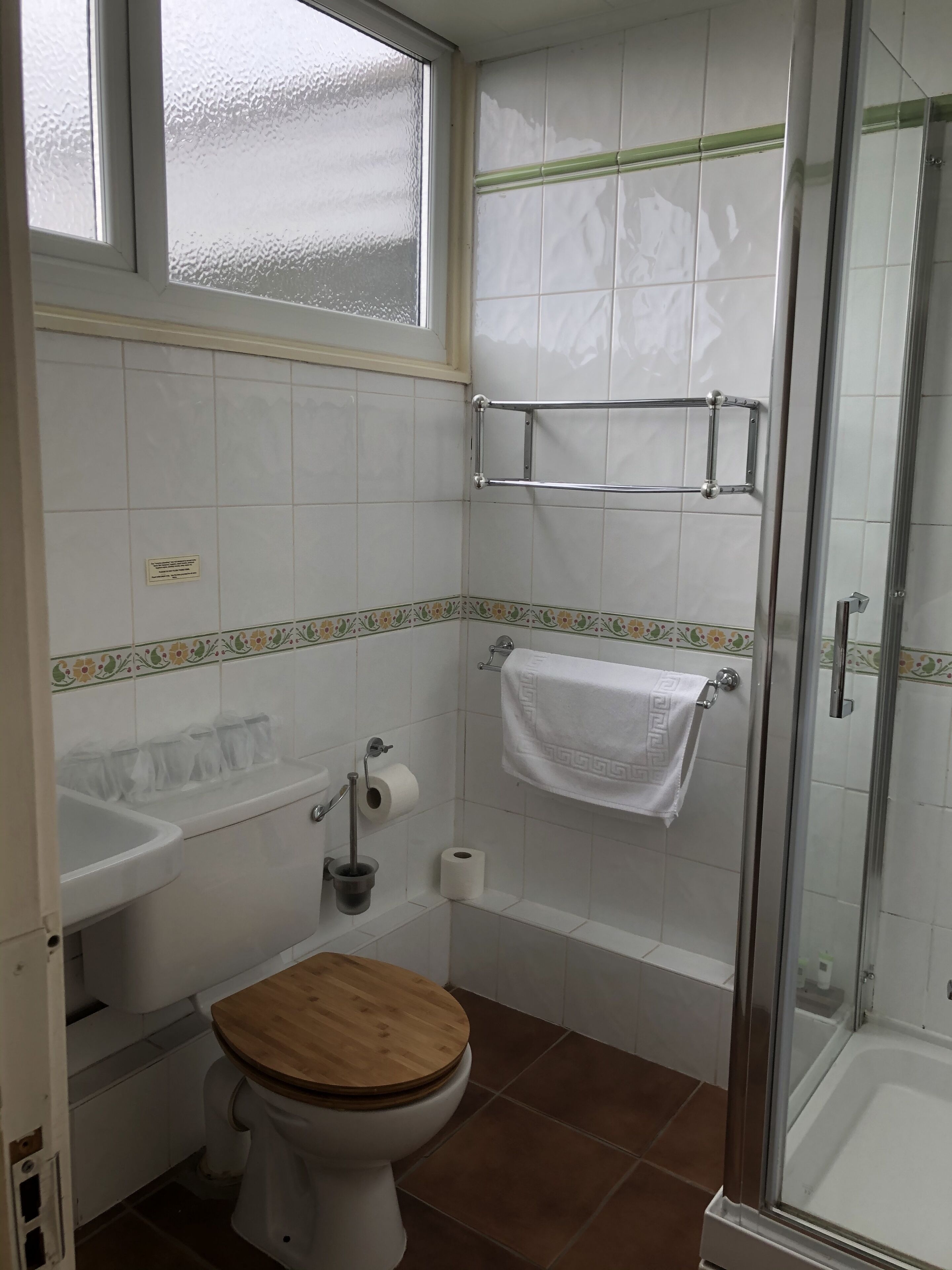 Un baño con inodoro, lavamanos, ducha y cabina de ducha con mampara de vidrio.