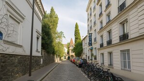 A cobblestone street lined with parked bicycles and a row of buildings with a sign indicating a hotel. - Hôtel du Parc Montsouris (Paris)