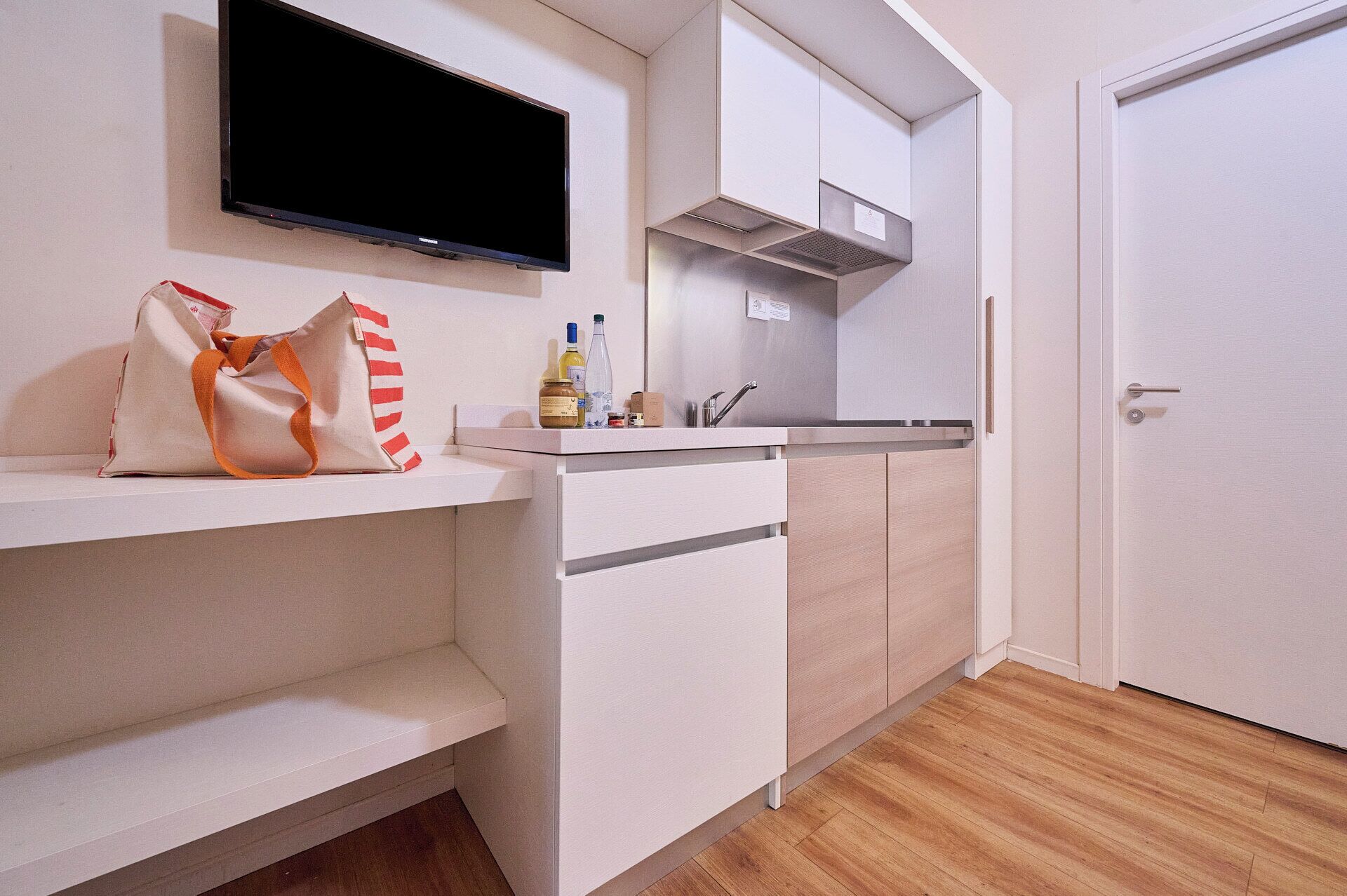 Una cocina moderna con televisor de pantalla plana, un lavamanos y armarios.