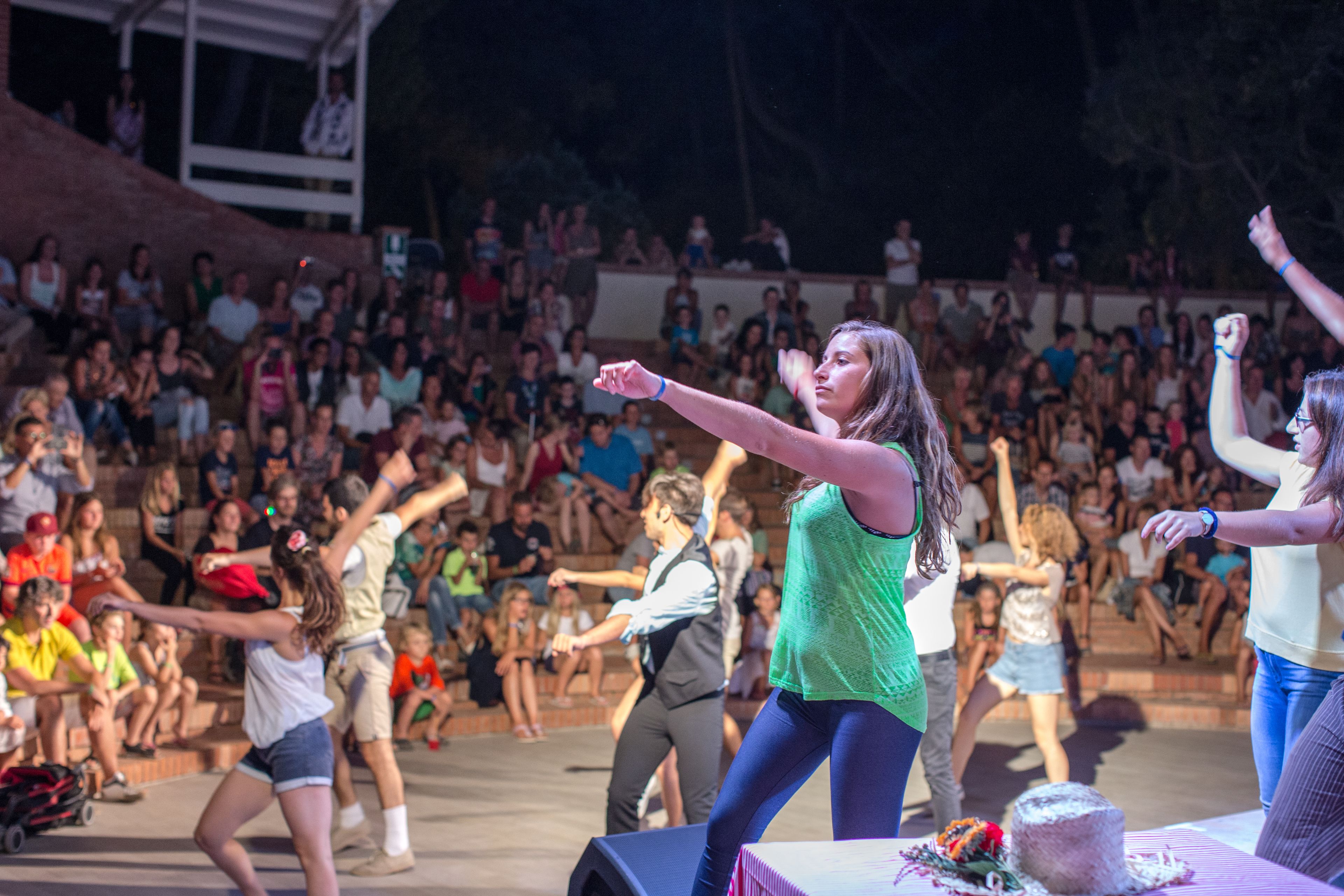 A stage with performers in front of a seated audience.