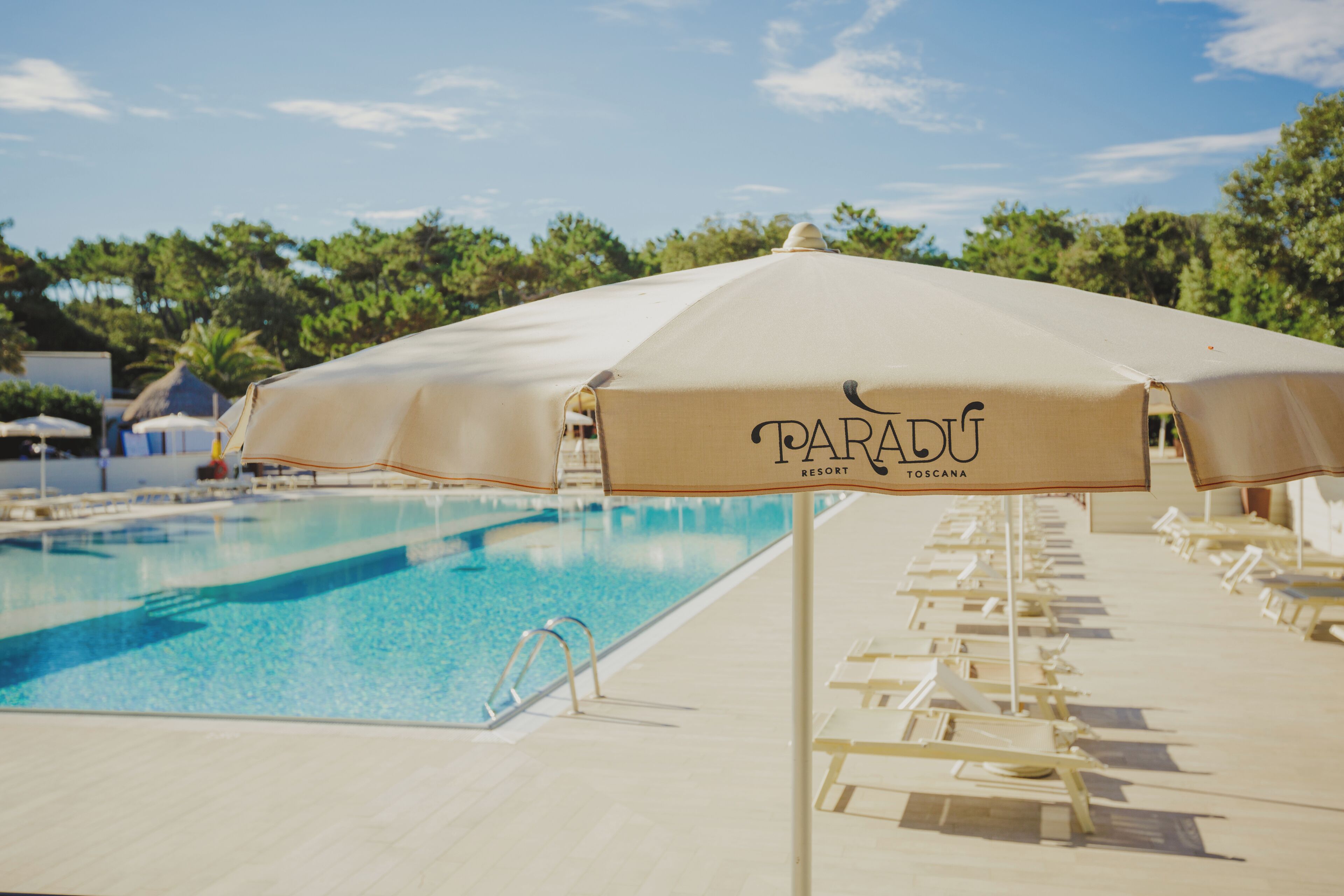 Area piscina con lettini e ombrelloni al Paradú Resort Toscana.