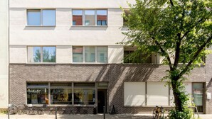 A two-story building with a coffee shop on the ground floor, outdoor seating, and a tree in front. - Pension Odin (Berlin)