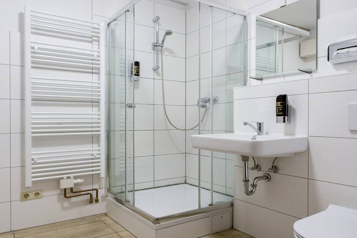 A modern bathroom with a glass shower enclosure, a white sink, and a toilet.