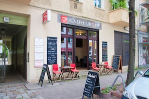 Un café avec une terrasse, un menu écrit à la craie et un panneau indiquant un prix de 3,20 € pour un café.