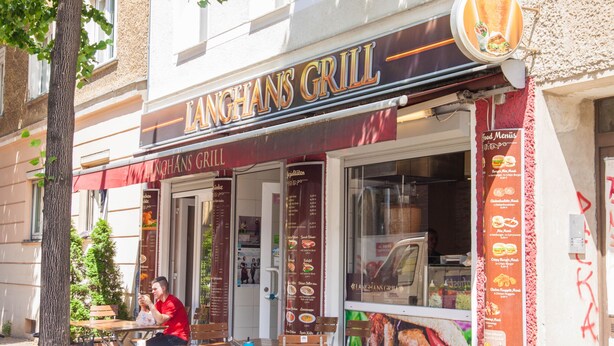 A restaurant named Langhans Grill with outdoor seating and a menu board. - Pension Odin (Berlin)