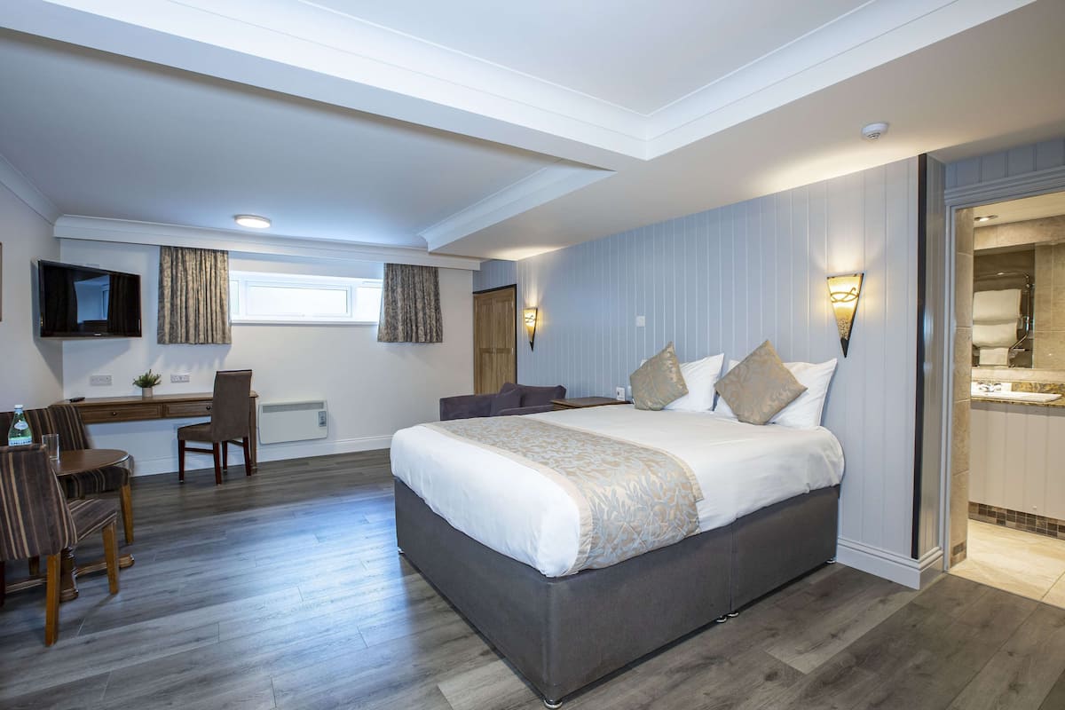 A bedroom with a large bed, a desk, and a chair.