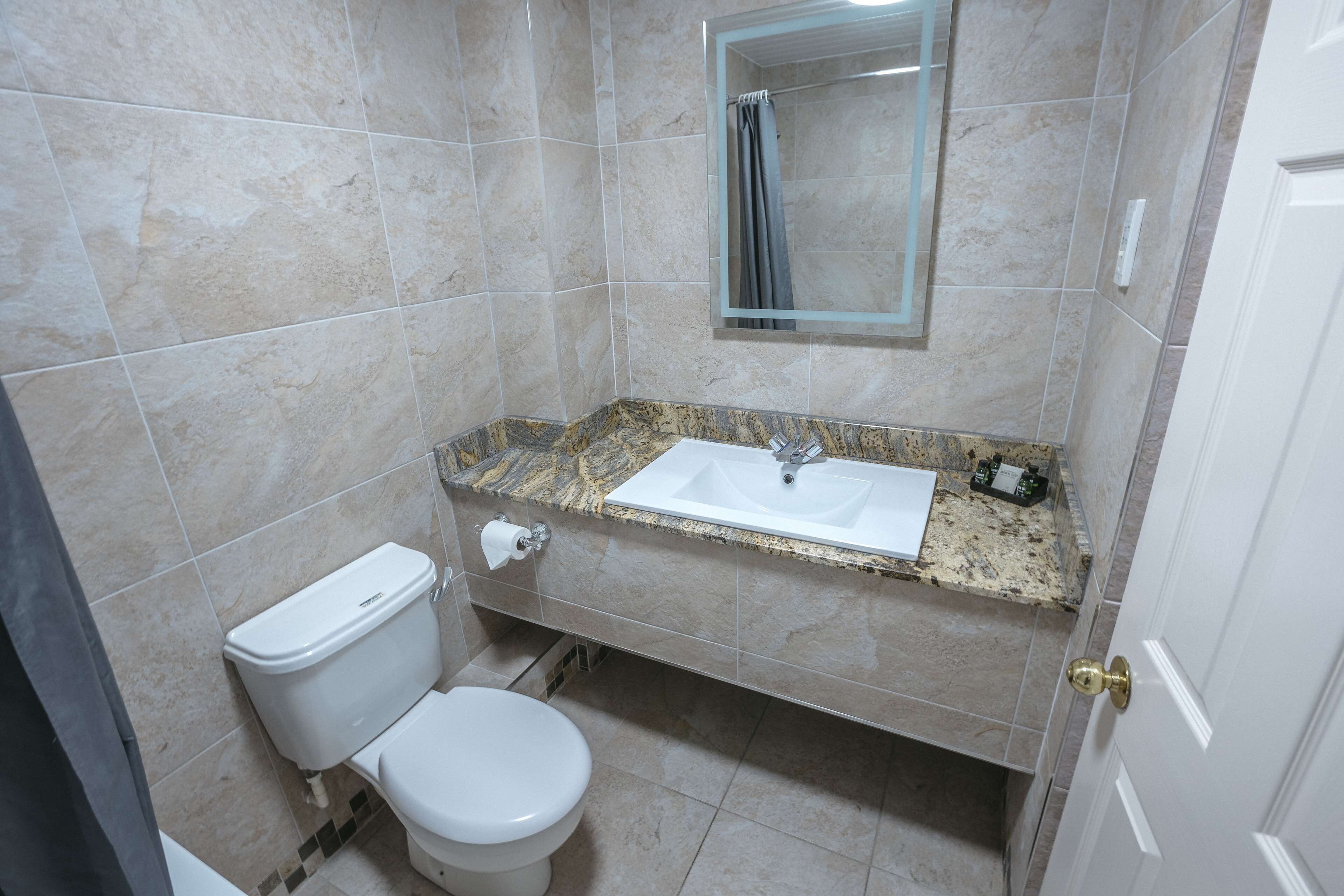 A bathroom with a toilet, sink, and mirror.