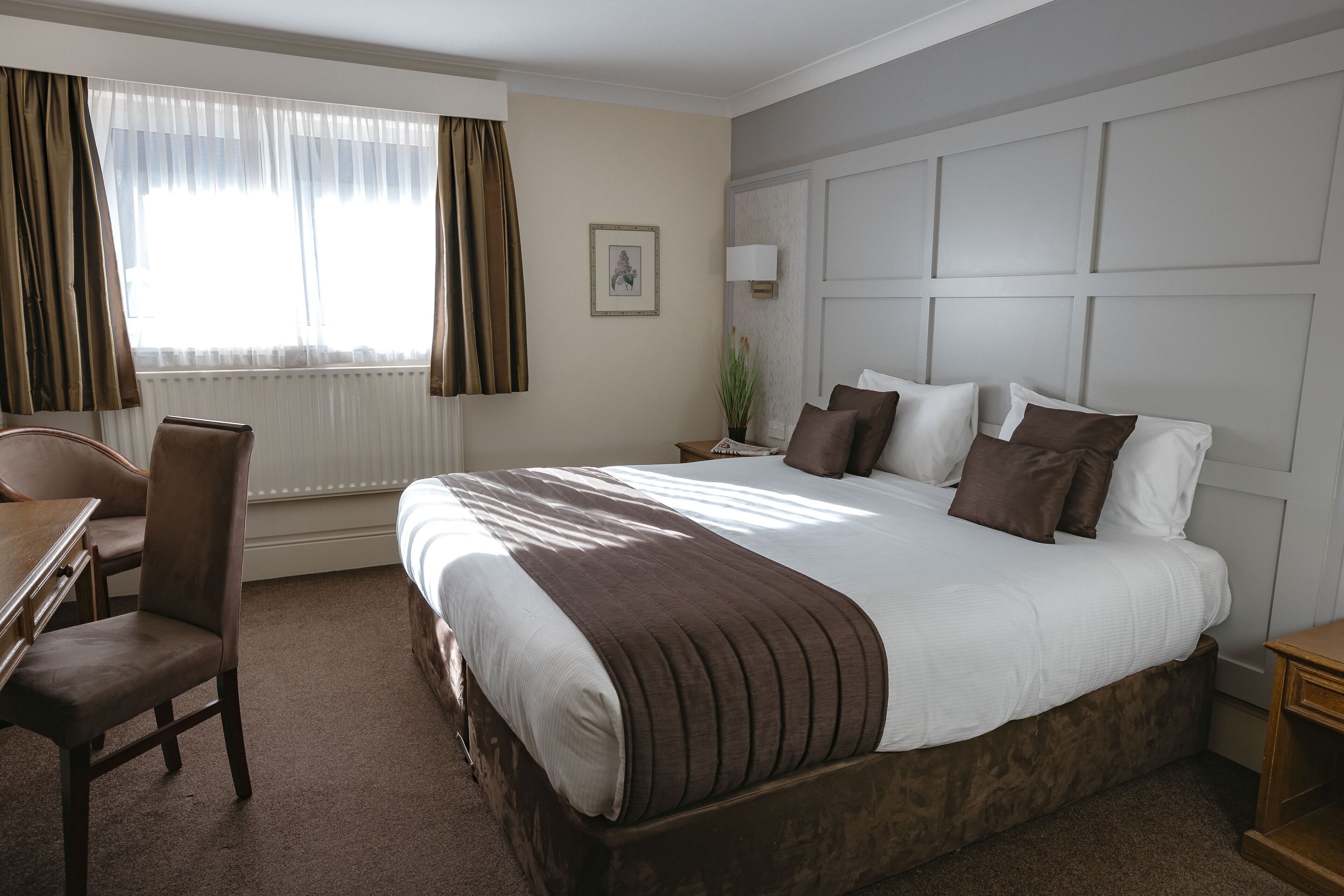 A hotel room with a large bed, a desk, and a chair.