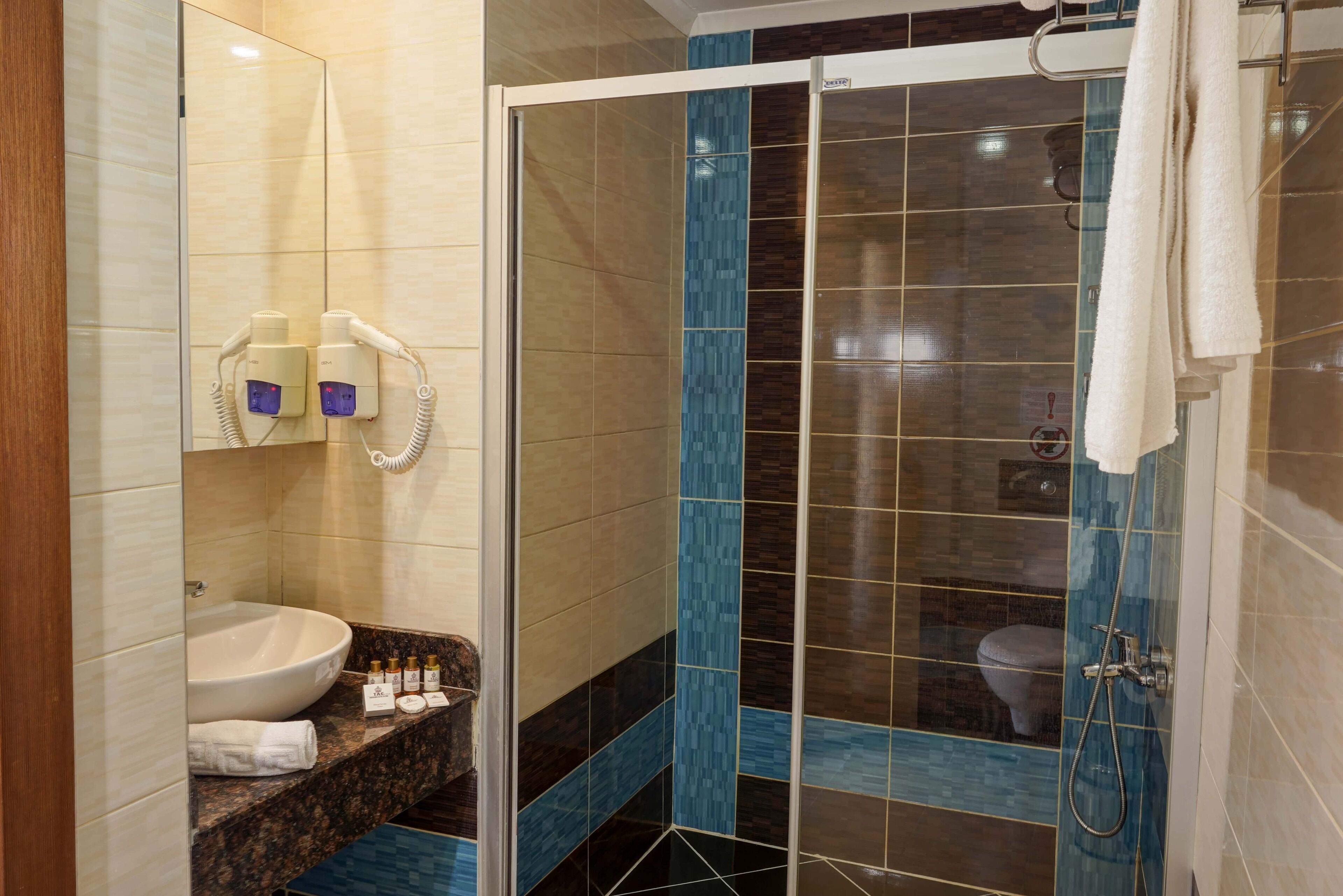 A bathroom with a sink, toiletries, a shower, and a glass door.