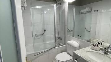 A modern bathroom with a glass-enclosed shower, a toilet, and a sink with a marble countertop.