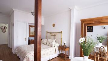 Quarto com estrutura de cama de madeira, mesa de cabeceira, espelho e arranjo floral.
