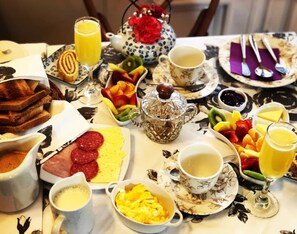 A breakfast table with various food items, including toast, eggs, sausages, and fruit. - Hotel Casa Somerscales (Valparaiso)