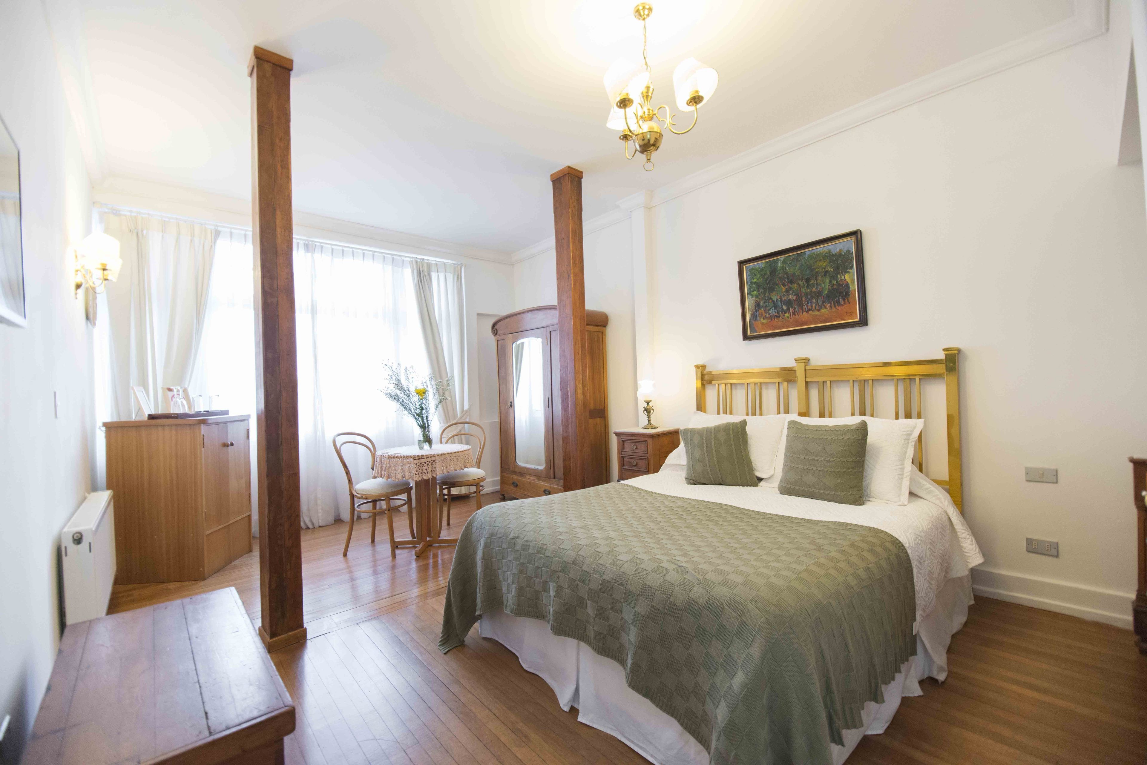 Ein Schlafzimmer mit einem Bett, Holzmöbeln, einer Chandelieber und einem Gemälde an der Wand.