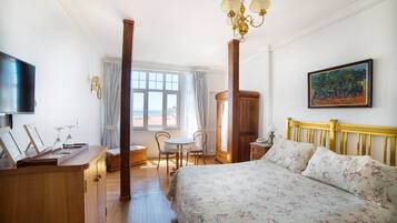 Un dormitorio con cama, cómoda de madera, televisor y un cuadro en la pared.