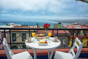 Un balcón con una mesa lista para el desayuno, con vistas a una ciudad costera.