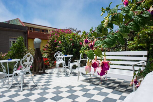 A checkered outdoor seating area with white metal furniture and a bench. - Hotel Casa Somerscales (Valparaiso)