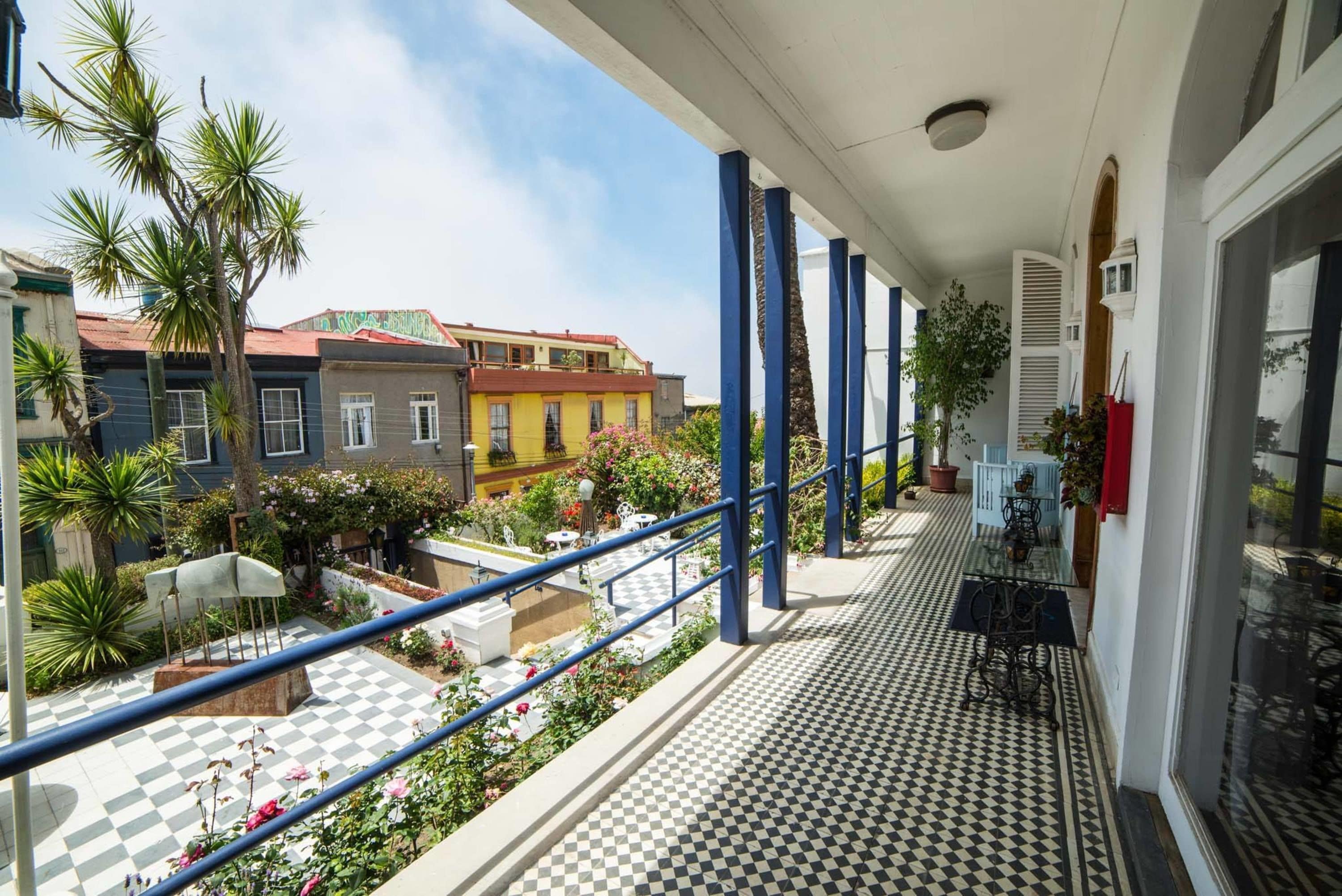 A balcony with a checkered floor, blue railings, and potted plants.