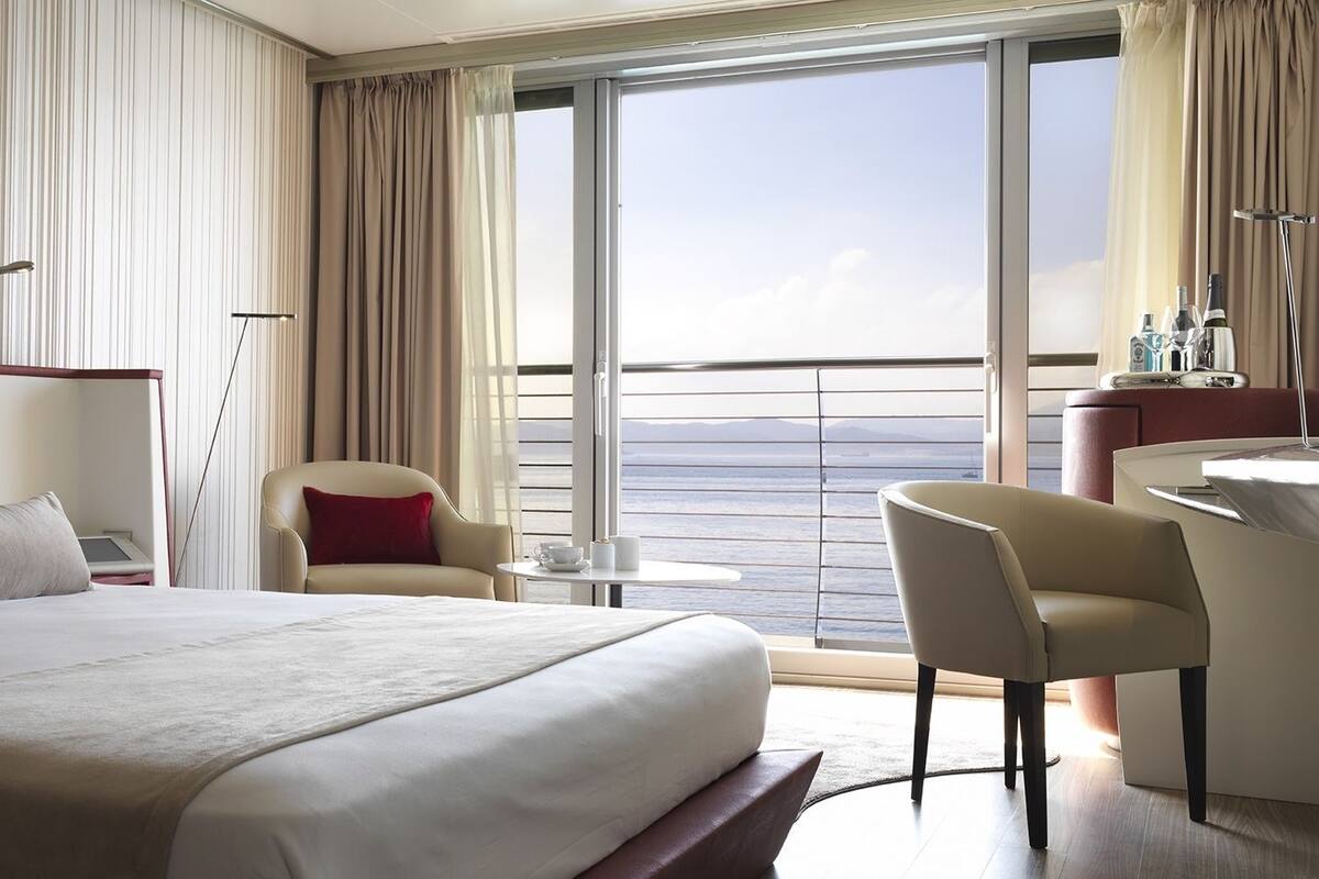 Ein Hotelzimmer mit einem großen Bett, einem Schreibtisch, einem Stuhl und Meerblick.