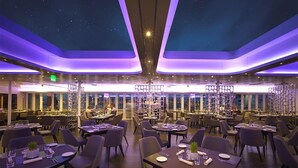 A spacious restaurant with multiple dining tables and chairs, a starry ceiling design, and large windows offering views of the city. - Sunborn Gibraltar Yacht Hotel Resort (Gibraltar)