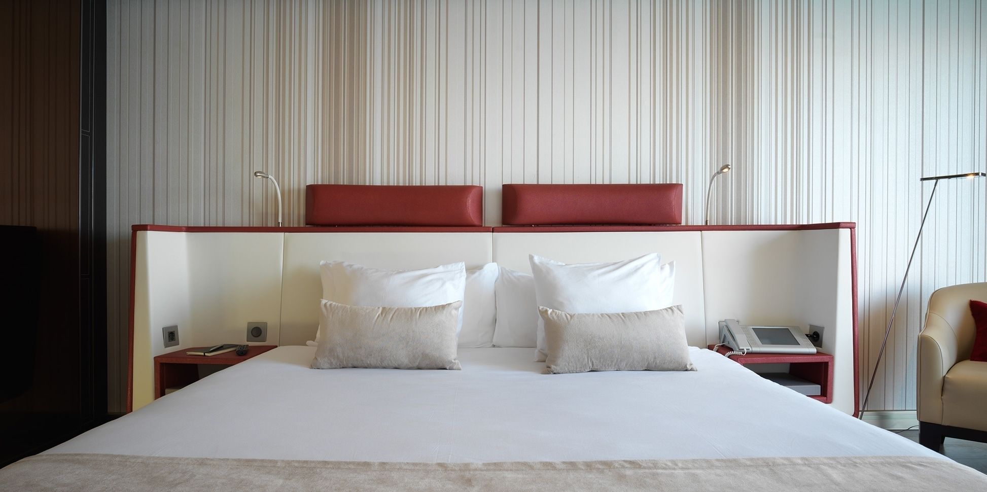 A hotel room with a large bed, two bedside tables, a telephone, and a lamp.