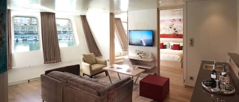 A modern interior with a sofa, a small table, a TV, and a kitchen area.