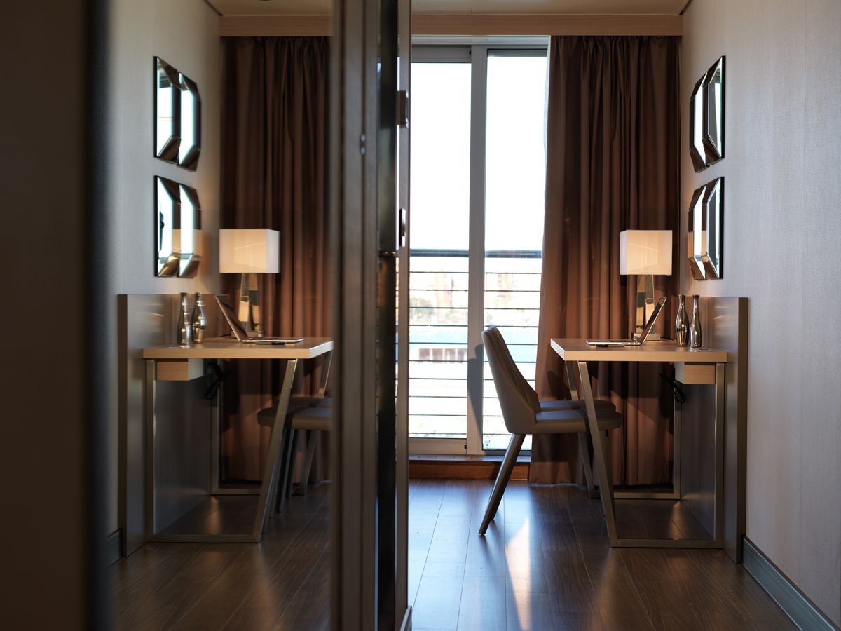 A hotel room with two desks, chairs, and lamps.
