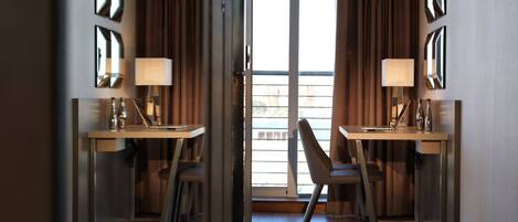 A hotel room with two desks, chairs, and lamps.