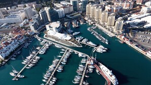 An aerial view of a marina with numerous boats docked, a large cruise ship, and surrounding high-rise buildings. - Sunborn Gibraltar Yacht Hotel Resort (Gibraltar)