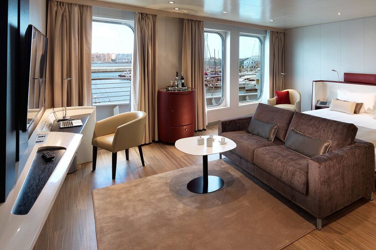 Ein modernes Hotelzimmer mit Bett, Sofa, Schreibtisch und Blick auf den Hafen.