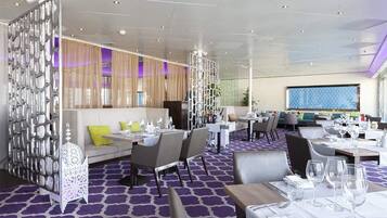 A modern restaurant with a purple patterned floor, white furniture, and a decorative white partition.