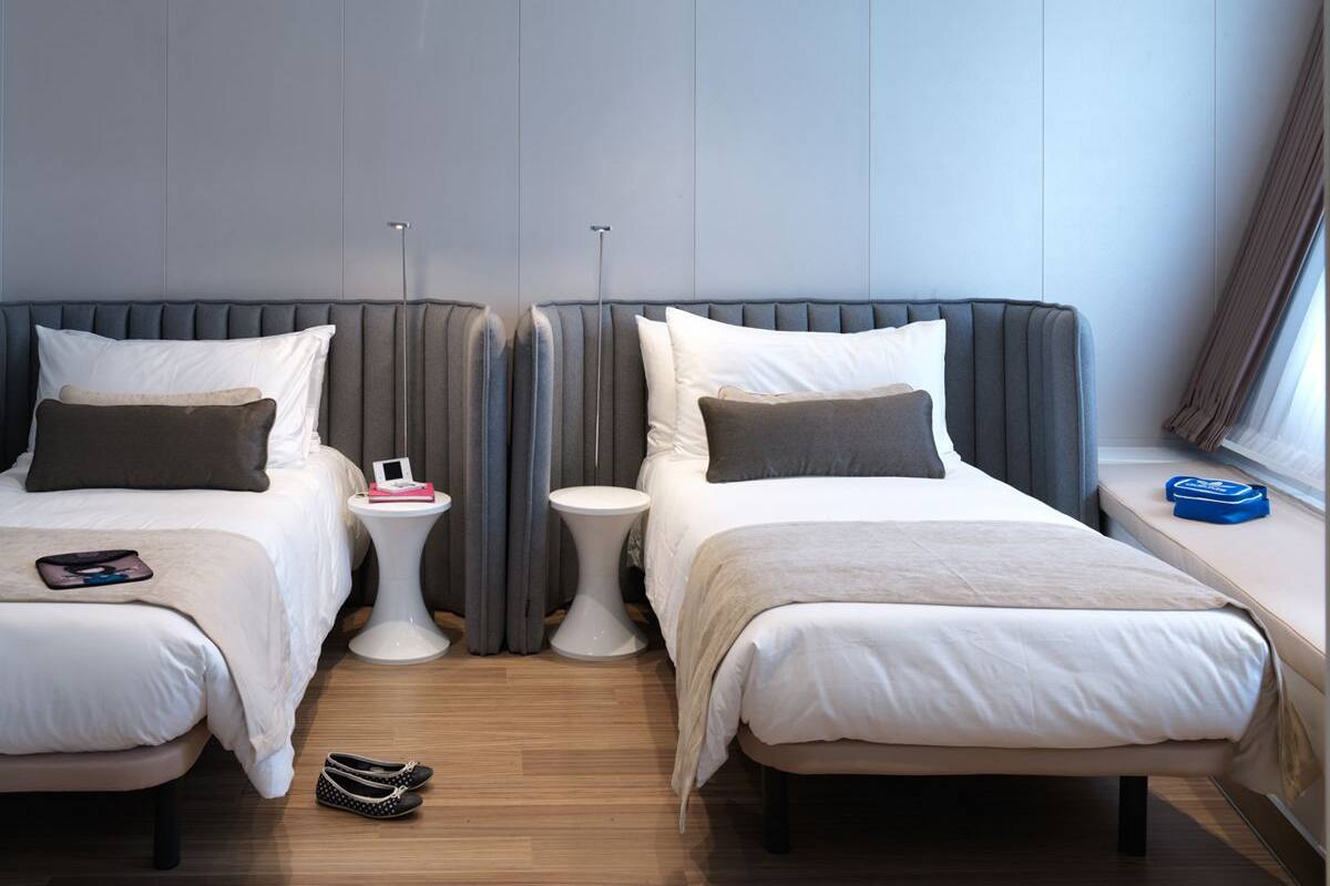 Ein Hotelzimmer mit zwei Betten, einem Nachttisch, einem kleinen runden Tisch und einem Fenster mit Vorhängen.