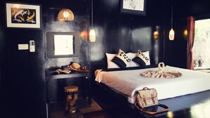 A bedroom with a bed, pillows, a bedside table, a lamp, and a window. - The Legend Maeklong (Samut Songkhram)