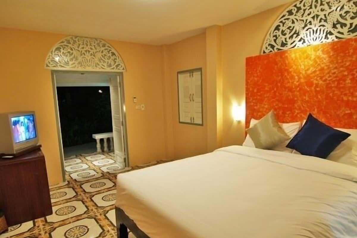 Habitación de hotel con una cama, un televisor sobre un atril de madera, baldosas de suelo estampadas y un panel decorativo en la pared.