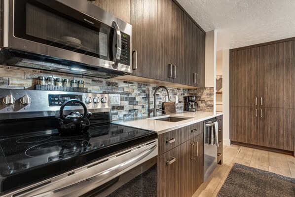A modern kitchen with stainless steel appliances, wooden cabinets, and a tiled backsplash. - Pioneer Park Rentals (Bend)