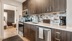 A modern kitchen with dark wood cabinets, stainless steel appliances, and a tiled backsplash. - Pioneer Park Rentals (Bend)