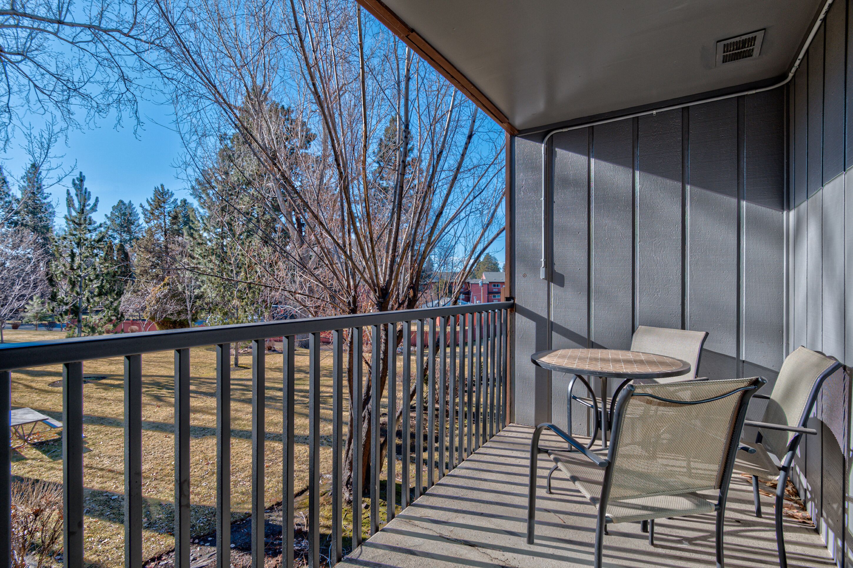 A balcony with a metal railing, a small round table, and two chairs.