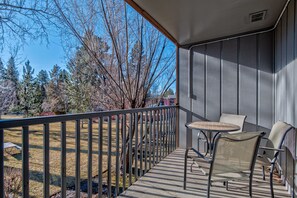 Un balcon avec une balustrade en métal, une petite table ronde et deux chaises.