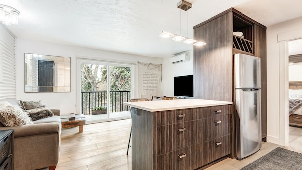 A modern kitchen with a central island, built-in appliances, and a dining area with a view to the outdoors. - Pioneer Park Rentals (Bend)