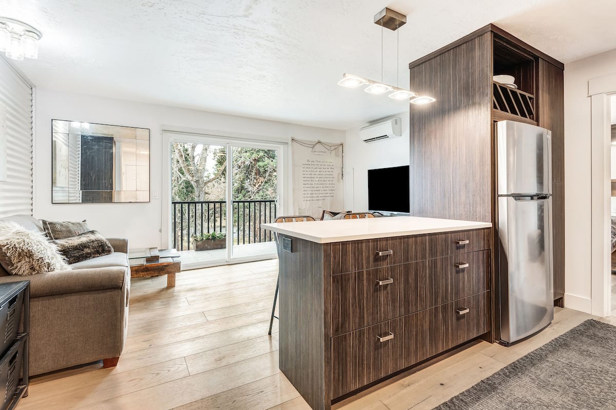 A modern kitchen with a central island, built-in appliances, and a dining area with a view to the outdoors.