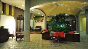 A hotel lobby with a large plant, seating area, and a Planet Hotel sign. - Planet Hotel (Maranello)