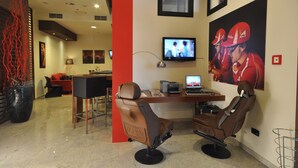 A modern room with two reclining chairs, a desk with a computer, and a TV mounted on the wall. - Planet Hotel (Maranello)