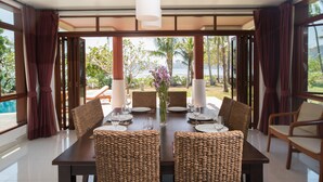 Comedor con una mesa grande dispuesta para seis personas, rodeado de sillas de mimbre, con vistas al exterior.